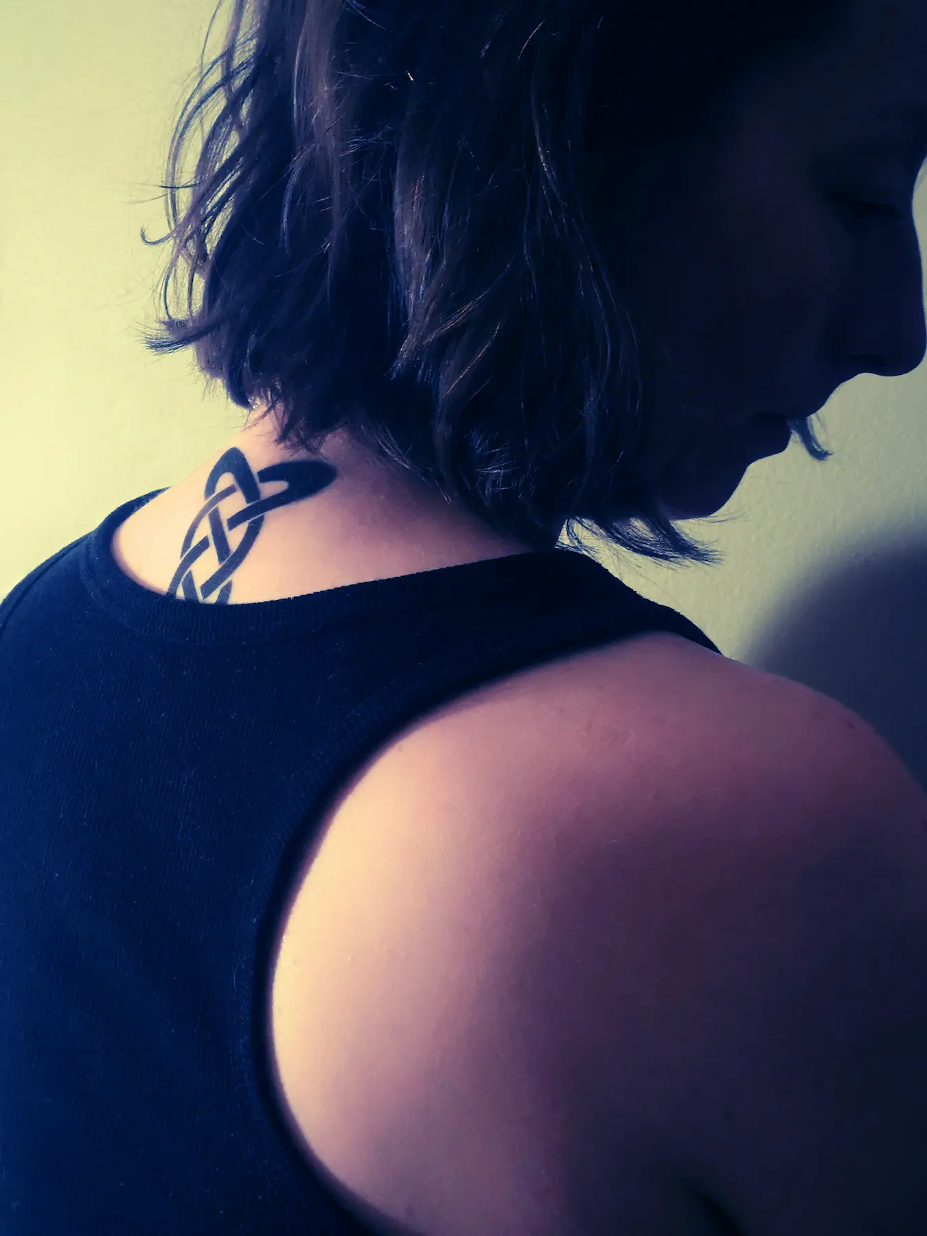 Person with a black Celtic knot tattoo on the back of their neck.